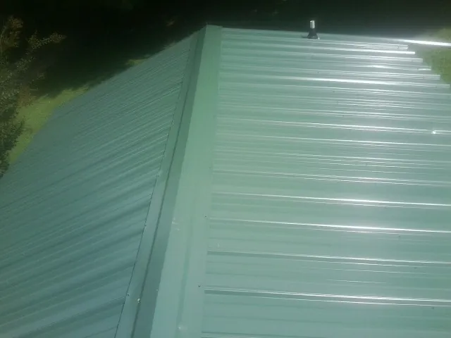 New green metal panels meeting at the ridge of a roof — Flat Roof Repair work by our crew in South Bound Brook