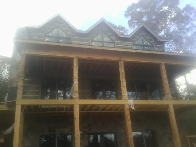 Dormers and porch framing on a large log home under construction — Roof Coating work by our crew in South Bound Brook