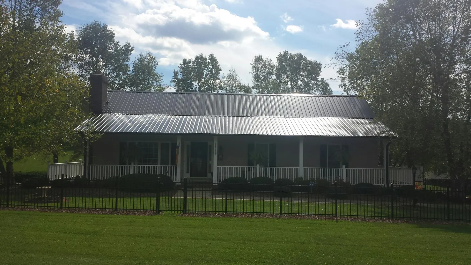 Gray metal roof on a brick ranch with a full width front porch — Gutter Guard Installation work by our crew in South Bound Brook