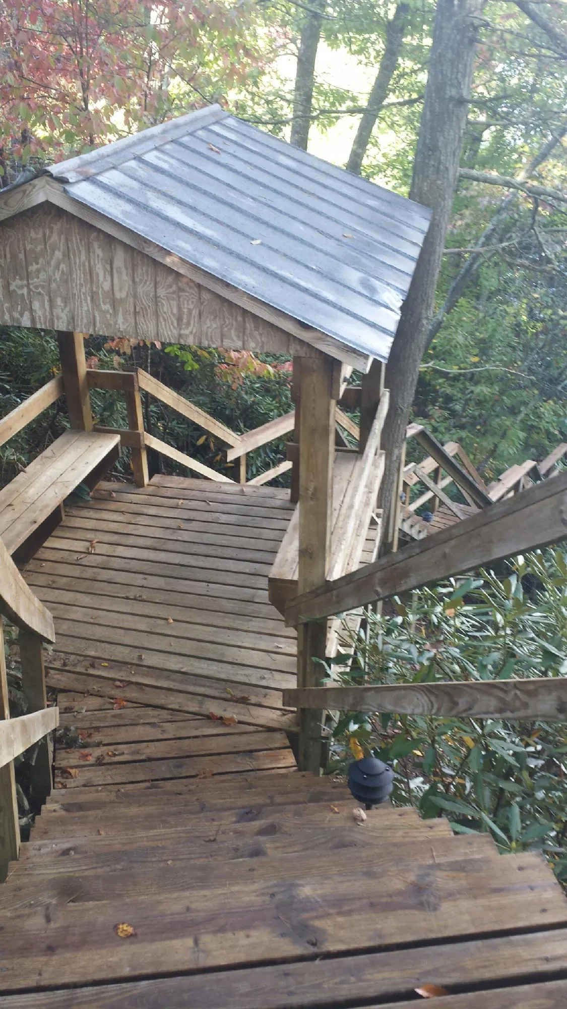 Metal roofed shelter over wooden steps on a wooded walkway — Skylight Repair & Installation work by our crew in South Bound Brook