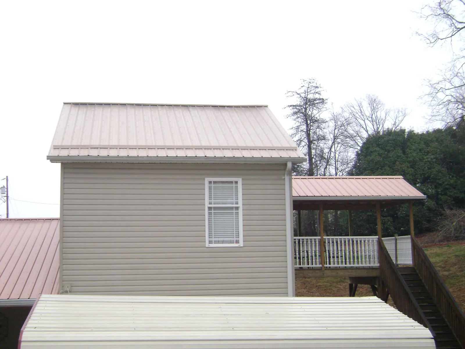 Tan metal roofs on a two story addition and attached porch, from a Roof Replacement job in South Bound Brook