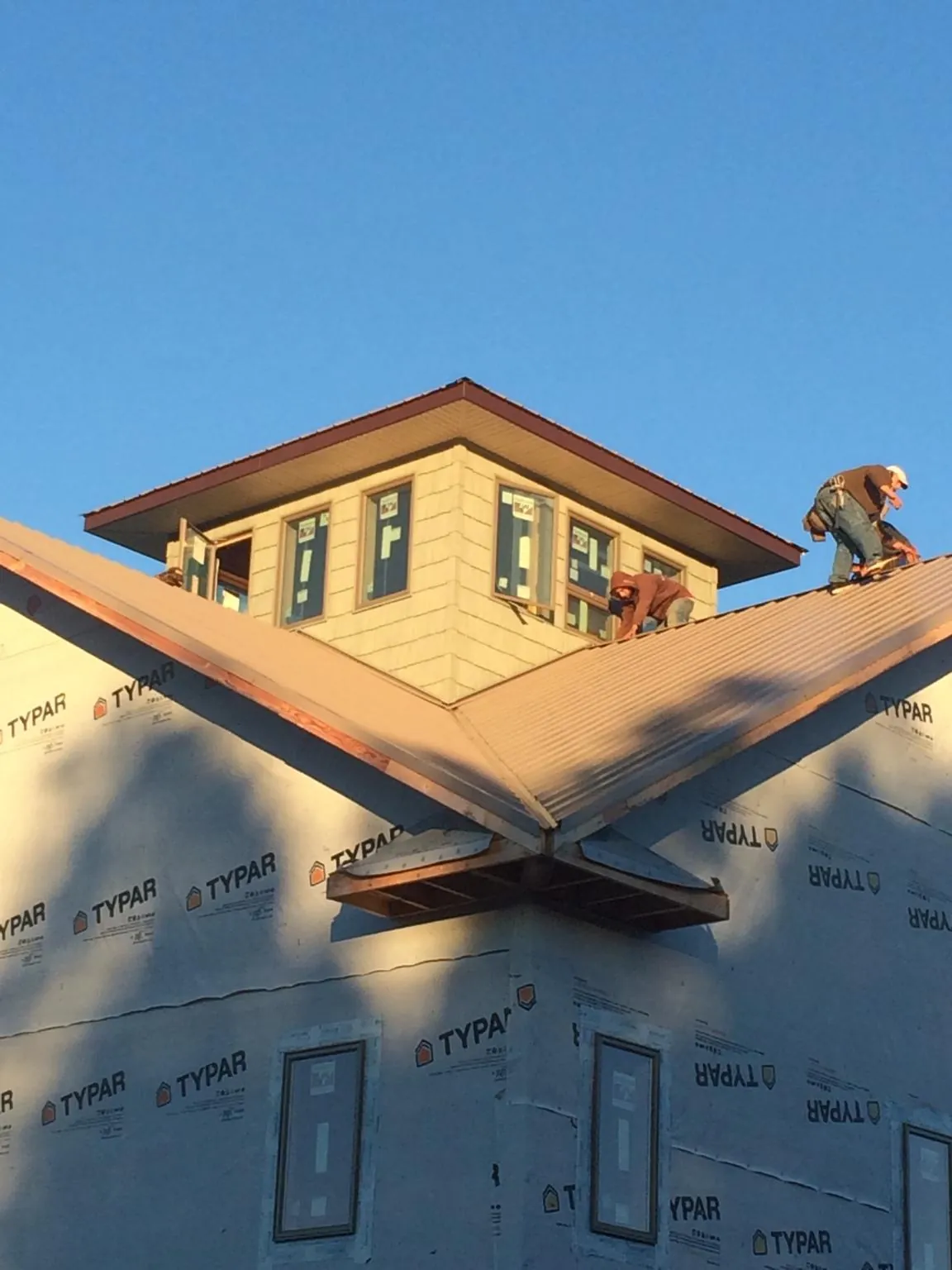 Roofers working around a rooftop cupola on a new metal roof at sunset — Roof Waterproofing in South Bound Brook by Roofing Brothers